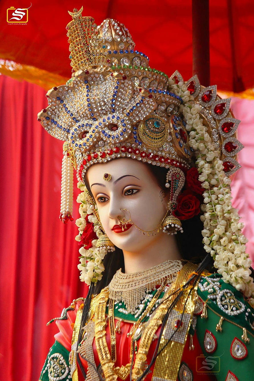 Ornate Goddess Statue with Golden Crown and Floral Garlands HD phone wallpaper