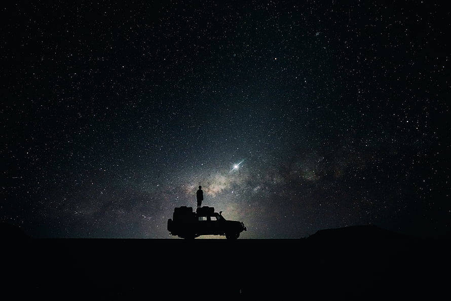 Silhouette of a person standing on an off-road vehicle under the Milky Way galaxy night sky HD wallpaper