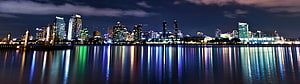 Panoramic City Skyline at Night with Colorful Water Reflections HD wallpaper