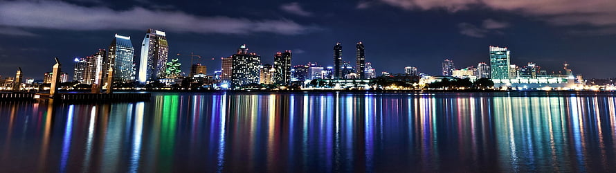 Panoramic City Skyline at Night with Colorful Water Reflections HD wallpaper