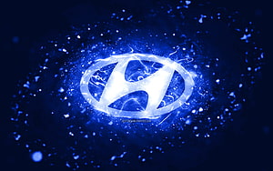Glowing Hyundai emblem with electric blue energy burst and particle effects on a dark abstract background HD wallpaper