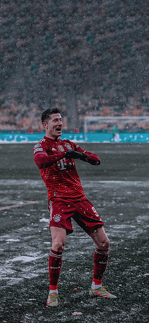 Robert Lewandowski in Bayern Munich kit celebrating on a snowy football pitch HD phone wallpaper