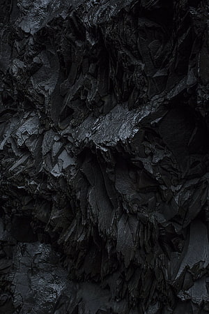 Dark volcanic rock texture with glossy black mineral surfaces and rugged natural formations HD phone wallpaper