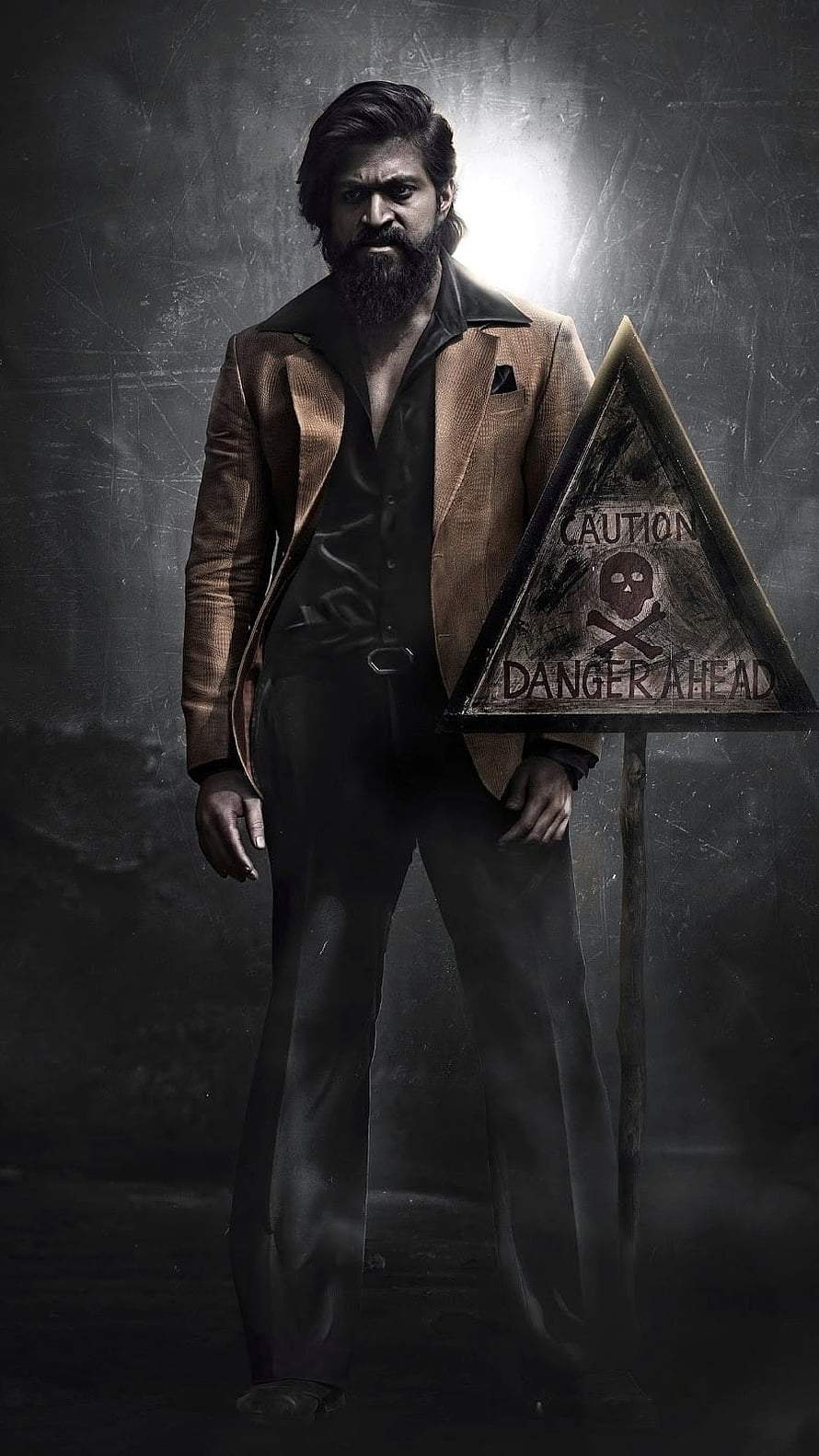 Allu Arjun as Pushpa Raj in a brown suit standing next to a danger sign HD phone wallpaper