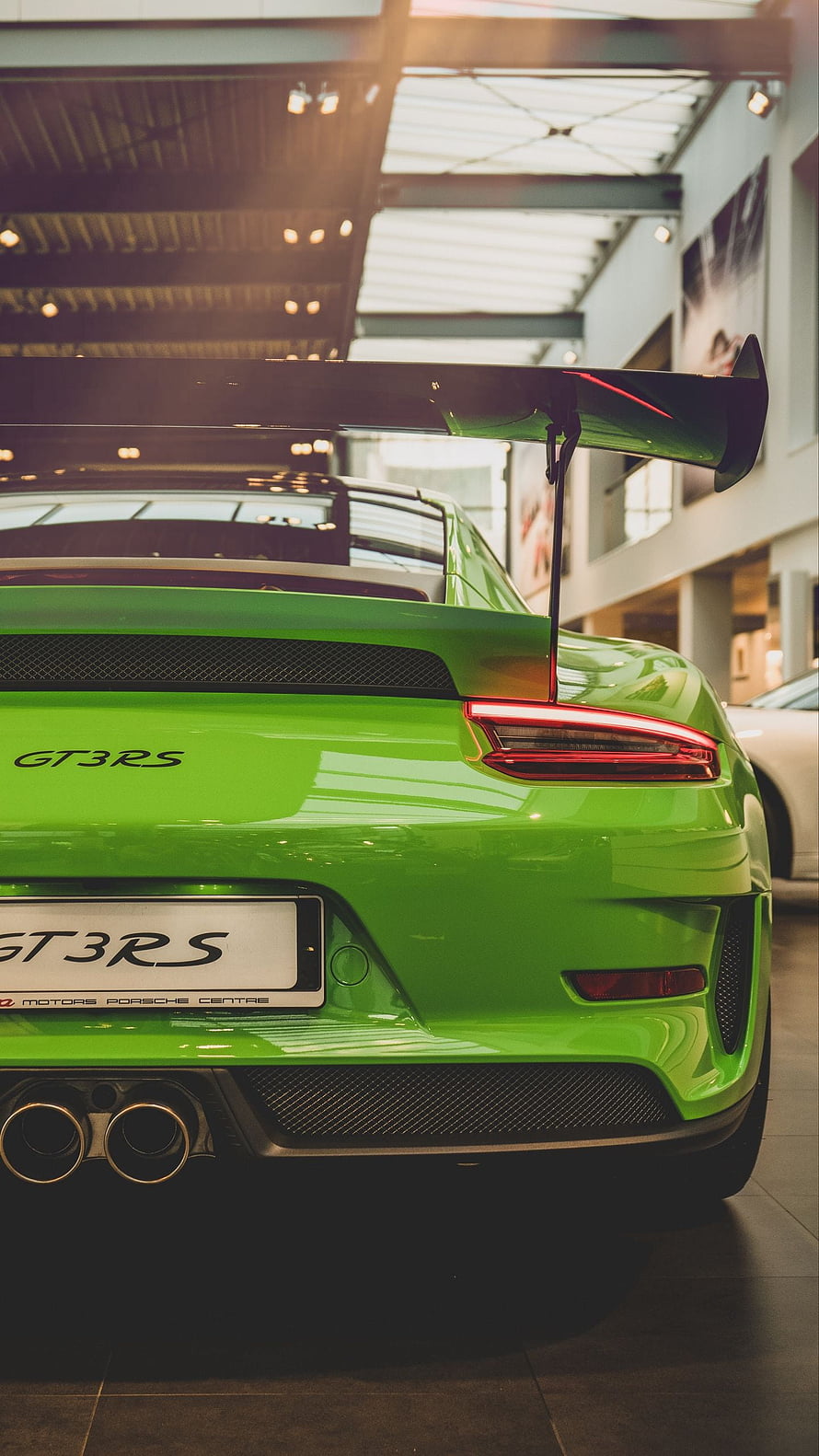 Rear View of a Green Porsche 911 GT3 RS with Large Rear Wing in a Showroom HD phone wallpaper
