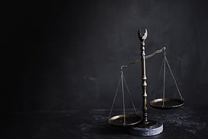 Vintage brass balance scale on a dark textured surface with dramatic moody lighting HD wallpaper