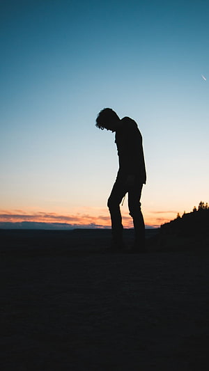 Silhouette of a person standing alone against a colorful sunset sky HD phone wallpaper