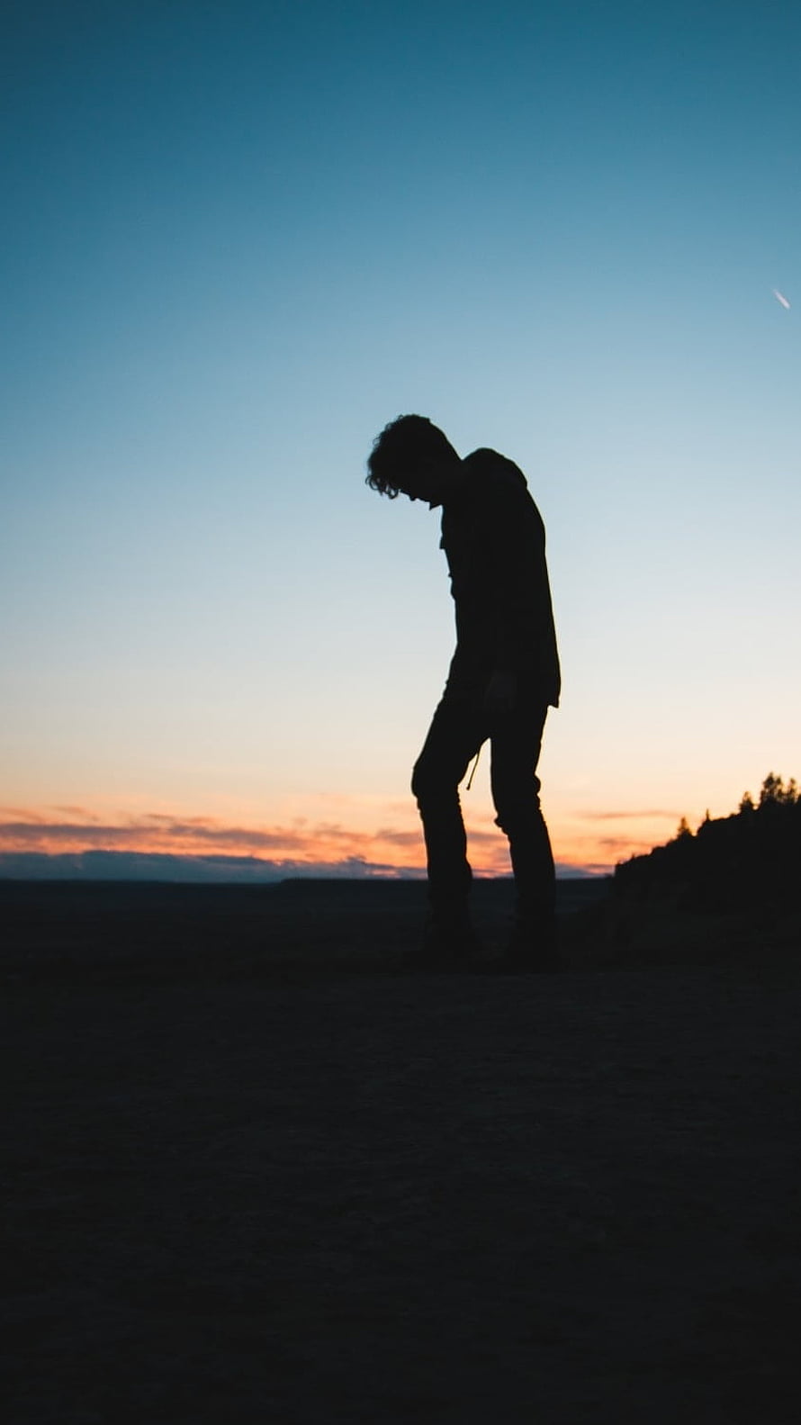 Silhouette of a person standing alone against a colorful sunset sky HD phone wallpaper