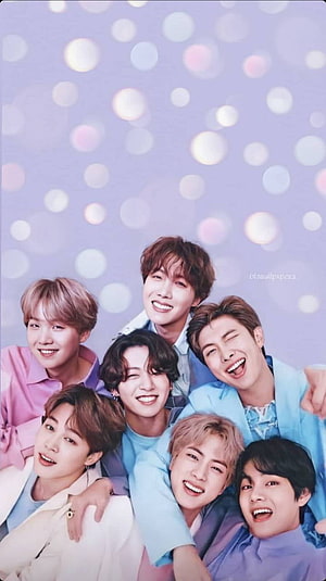 BTS Members Smiling Together in Pastel Tones Against a Soft Bokeh Background HD phone wallpaper