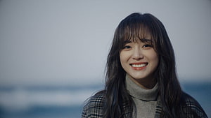 Kim Se Jeong smiling portrait in a plaid coat and turtleneck against a soft ocean backdrop HD wallpaper