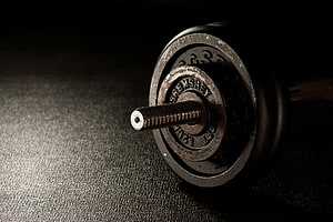 Close-up of a vintage Sremshay dumbbell with textured rubber plates on a dark surface HD wallpaper