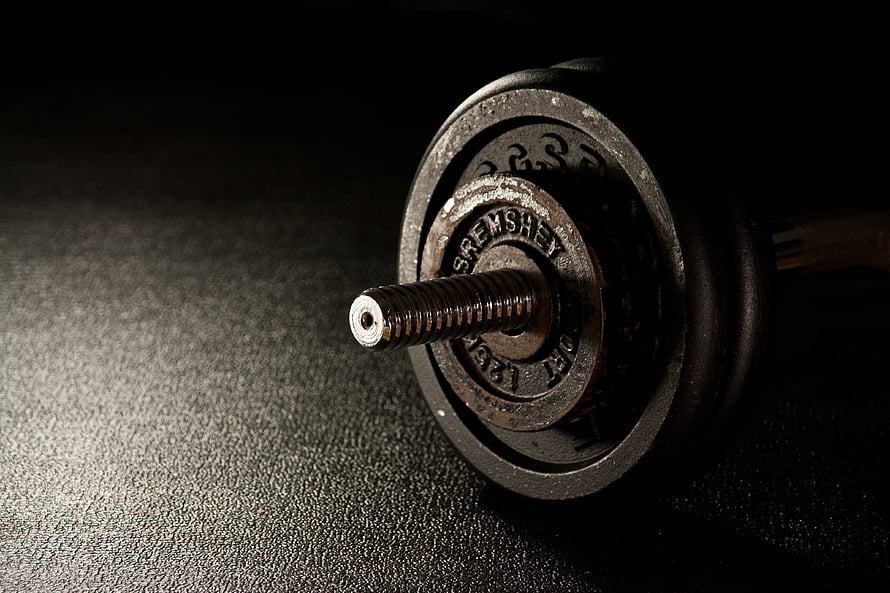 Close-up of a vintage Sremshay dumbbell with textured rubber plates on a dark surface HD wallpaper
