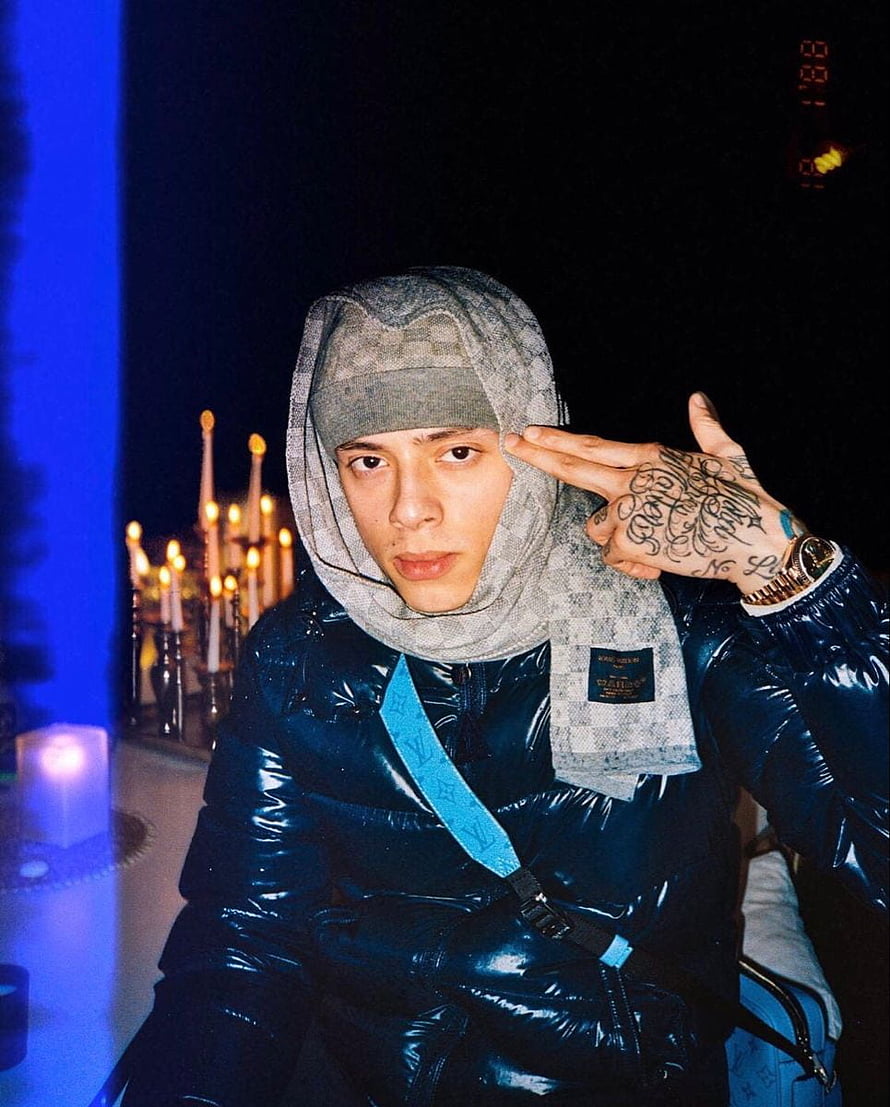 Central Cee in a glossy blue puffer jacket and patterned headscarf making a hand gesture at night HD phone wallpaper