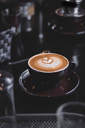 Dark moody cappuccino with heart latte art in a black ceramic cup on a reflective surface HD phone wallpaper