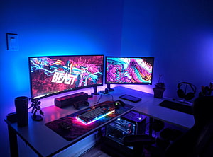 Neon Blue and Purple Gaming Setup with Dual Monitors and RGB Keyboard HD wallpaper