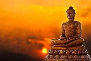 Serene Buddha Statue in Meditation Against a Golden Sunrise Sky HD wallpaper