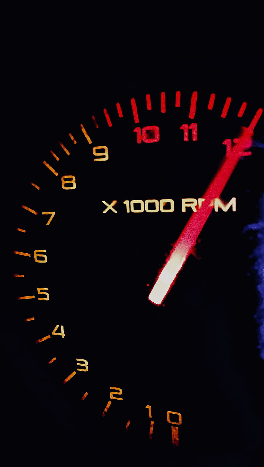 Close-up of a glowing red tachometer needle pointing to high RPM on a dark dashboard HD phone wallpaper