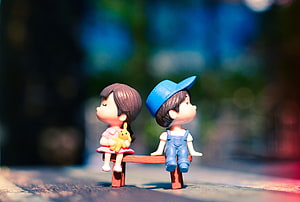 Cute Miniature Doll Couple Sitting on a Tiny Bench with Soft Bokeh Background HD wallpaper