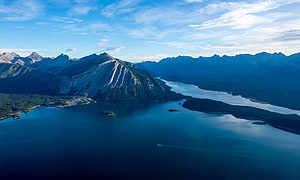 Aerial View of Majestic Mountains and Deep Blue Lake with Forested Shores HD wallpaper