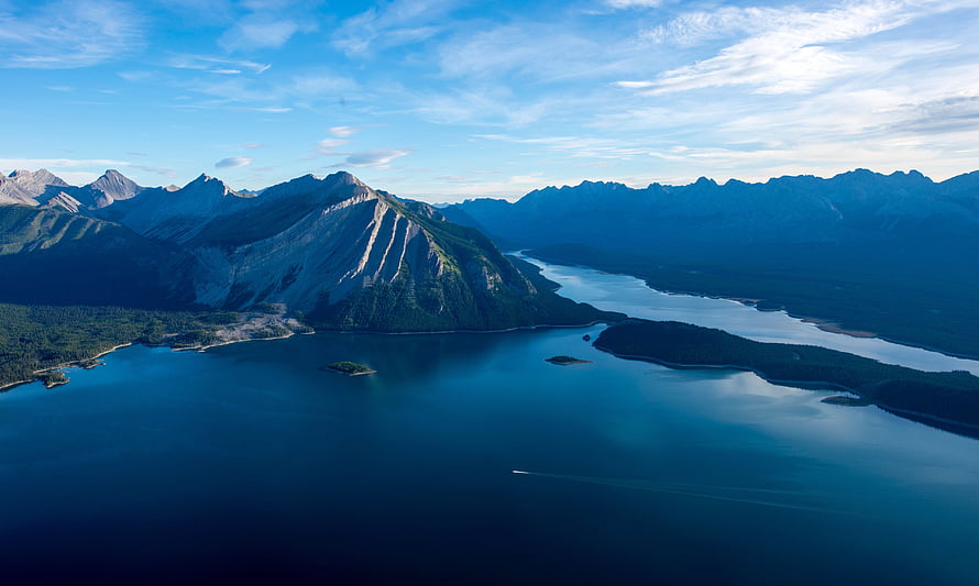 Aerial View of Majestic Mountains and Deep Blue Lake with Forested Shores HD wallpaper