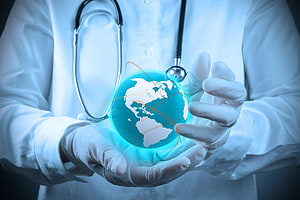 Doctor in White Coat Holding Glowing Holographic Globe with Stethoscope HD wallpaper