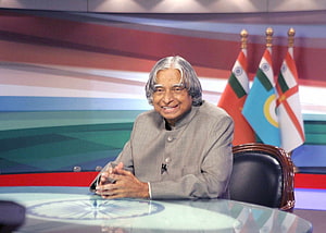 APJ Abdul Kalam Seated at a News Desk with Indian Flags in the Background HD wallpaper