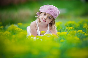 Cute Little Girl in Pink Hat Lying in a Field of Yellow Flowers HD wallpaper