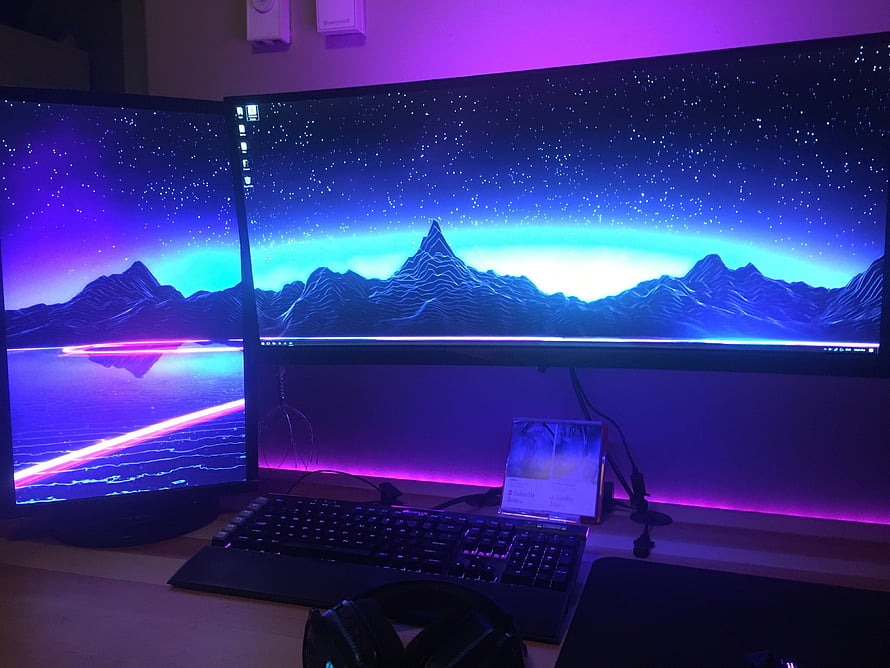 Dual Monitor Gaming Setup With Neon Purple Ambient Lighting And Synthwave Mountain Wallpaper HD wallpaper