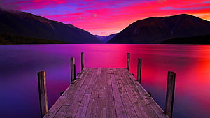 Vibrant Sunset Over a Wooden Dock Extending Into a Calm Mountain Lake HD wallpaper