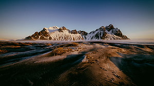 Snow-Capped Mountain Range Rising Above a Vast Frozen Tundra at Golden Hour HD wallpaper