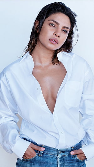 Priyanka Chopra in an open white shirt and denim jeans against a light background HD phone wallpaper