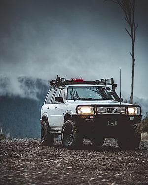 White Nissan Patrol off-road SUV with roof rack and bull bar on a gravel mountain overlook HD phone wallpaper