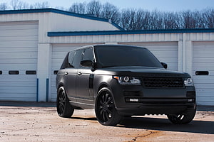 Matte Black Range Rover SUV with Custom Black Alloy Wheels Parked in Front of Industrial Garage HD wallpaper