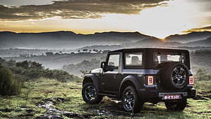 Mahindra Thar SUV parked on grassy hillside at sunset with mountains HD wallpaper