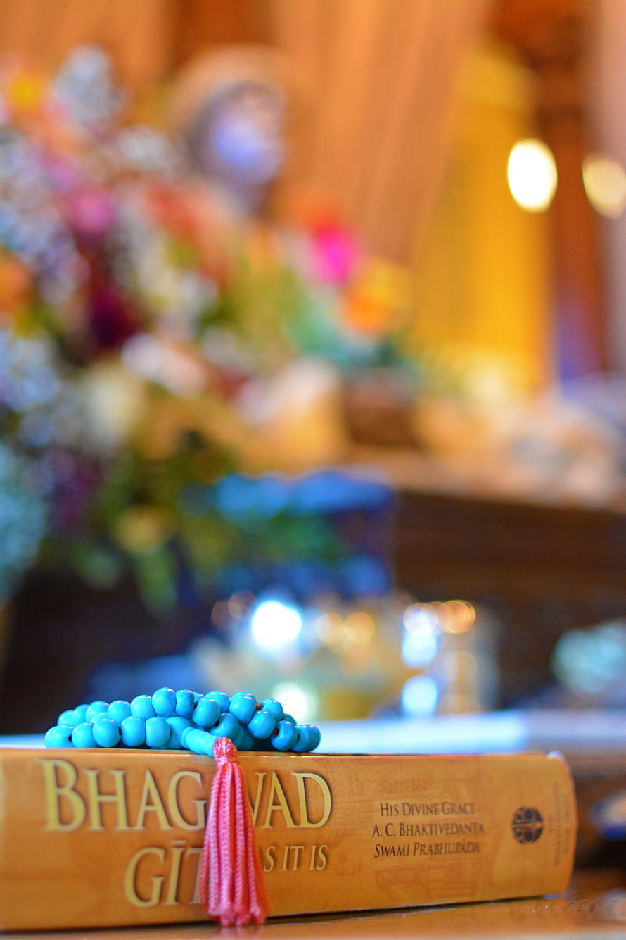 Bhagavad Gita As It Is book with blue prayer beads and pink tassel on wooden surface HD phone wallpaper