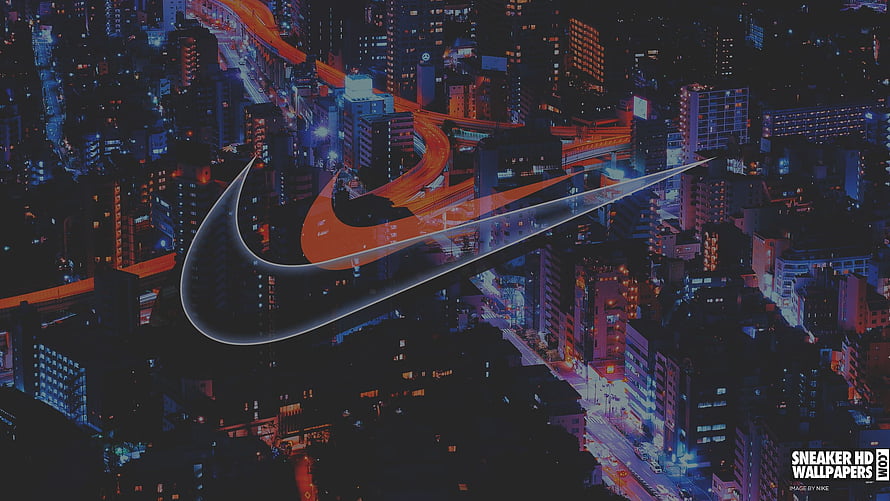 Nike Swoosh Logo Over Aerial Night Cityscape With Glowing Orange Highway Lights HD wallpaper