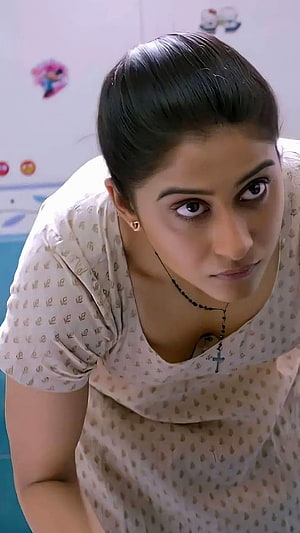 Woman with dark hair in a bun wearing a patterned top and cross necklace looking up intensely, Regina Cassandra, tamil actress HD phone wallpaper