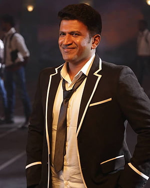 Puneeth Rajkumar in a black tuxedo jacket with white piping and a dark tie HD phone wallpaper