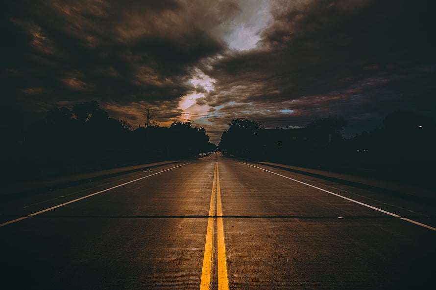 Moody Two-Lane Highway Stretching Into a Dramatic Overcast Sky at Dusk HD wallpaper