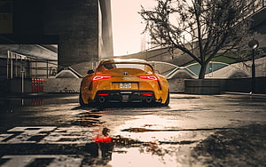 Rear View of a Yellow Toyota Supra Parked on a Wet Urban Street HD wallpaper