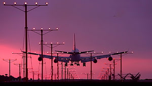 Commercial Jetliner Silhouette Approaching Runway at Dusk with Airport Lighting HD wallpaper