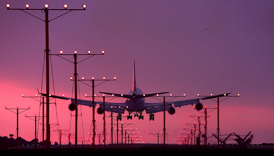 Commercial Jetliner Silhouette Approaching Runway at Dusk with Airport Lighting HD wallpaper
