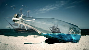 Pirates of the Caribbean ship sailing inside a glass bottle on a sandy beach HD wallpaper