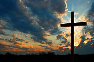 Silhouette of a Christian Cross Against a Dramatic Sunset Sky with Sun Rays HD wallpaper