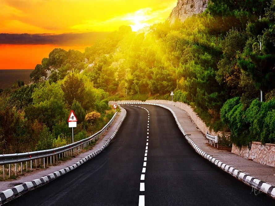 Winding Mountain Road at Golden Sunset with Lush Green Trees and Ocean View HD wallpaper