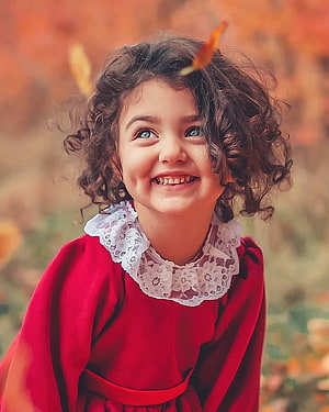 Smiling Curly-Haired Girl in Red Dress with Autumn Leaves HD phone wallpaper