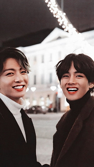 BTS V and Jungkook smiling together in winter coats with city lights background HD phone wallpaper
