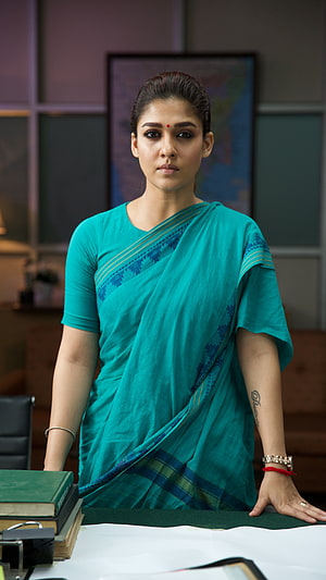Nimisha Sajayan in a teal saree standing in an office setting HD phone wallpaper