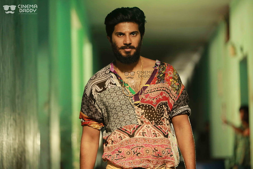 Dulquer Salmaan in a colorful patchwork shirt standing in a green corridor HD wallpaper