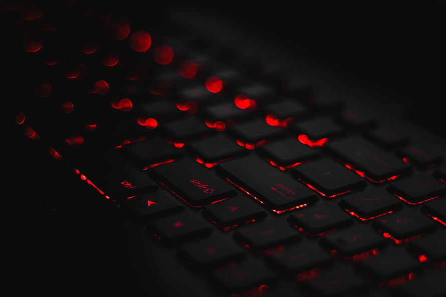 Close-up of a black mechanical keyboard with intense red backlighting and bokeh effects HD wallpaper